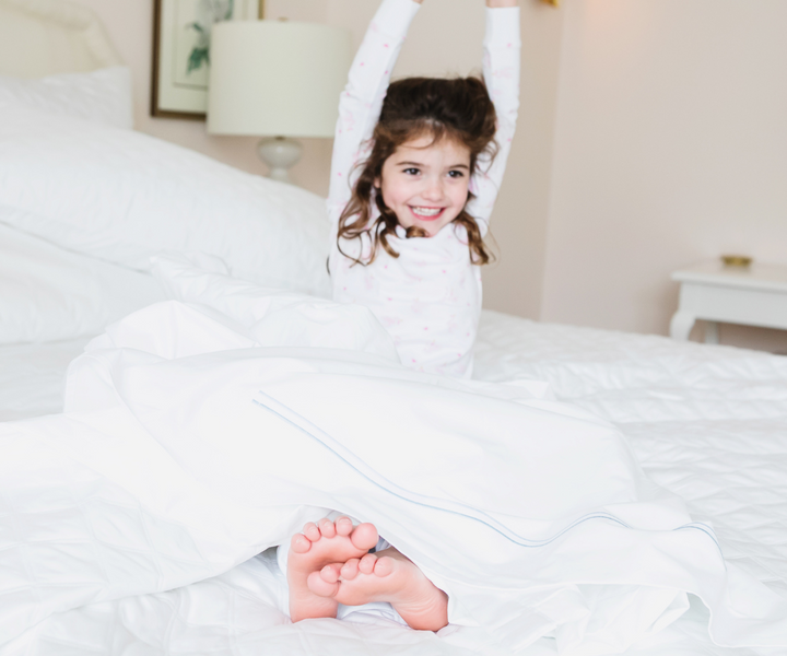 kid streching in white flat sheet with 2 blue stripes
